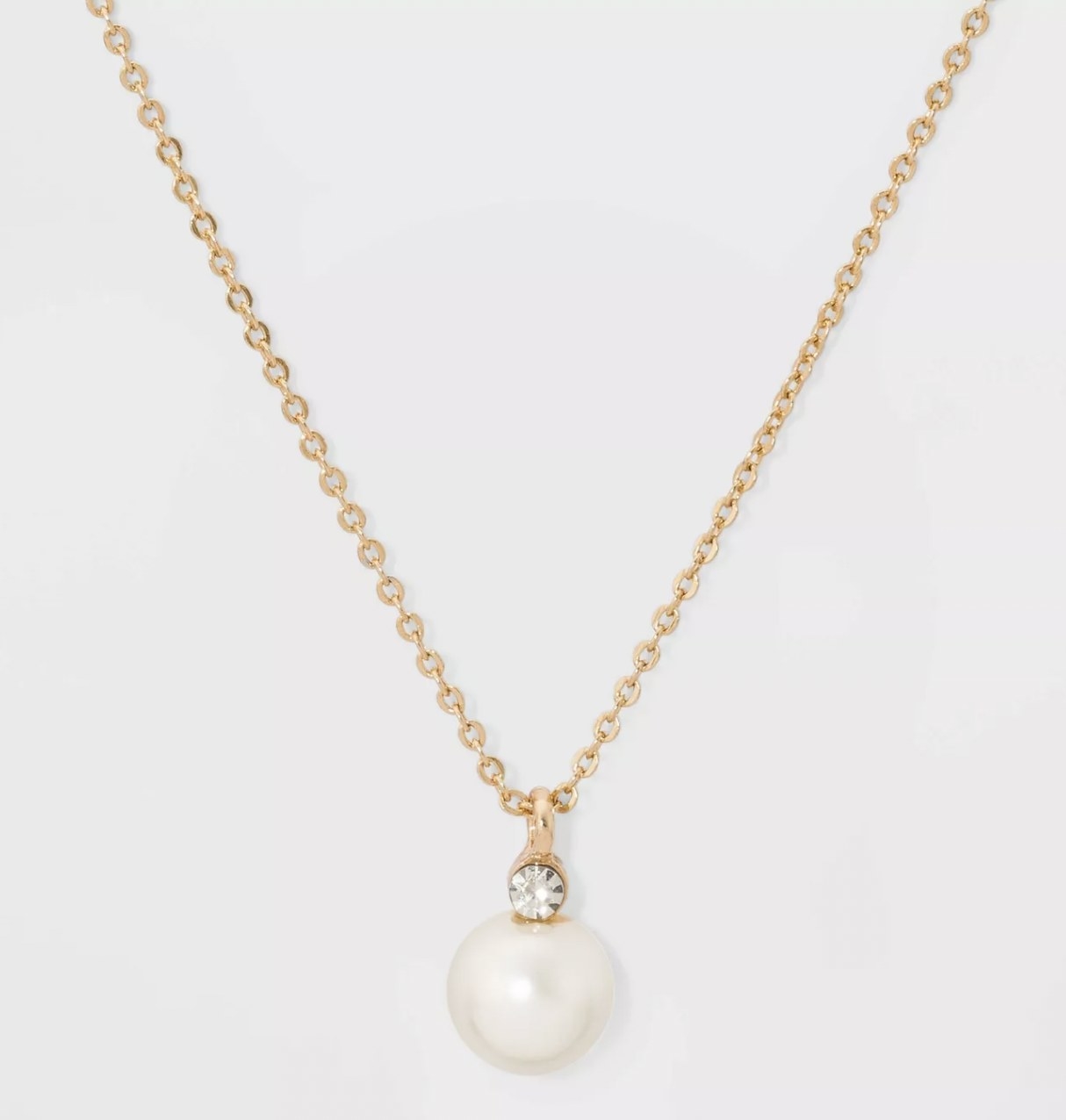 a gold chain with a pearl pendant and a small gemstone