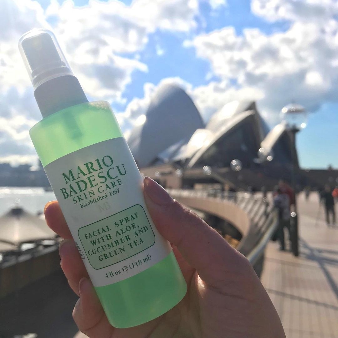 A person holding up a bottle of Mario Badescu mist