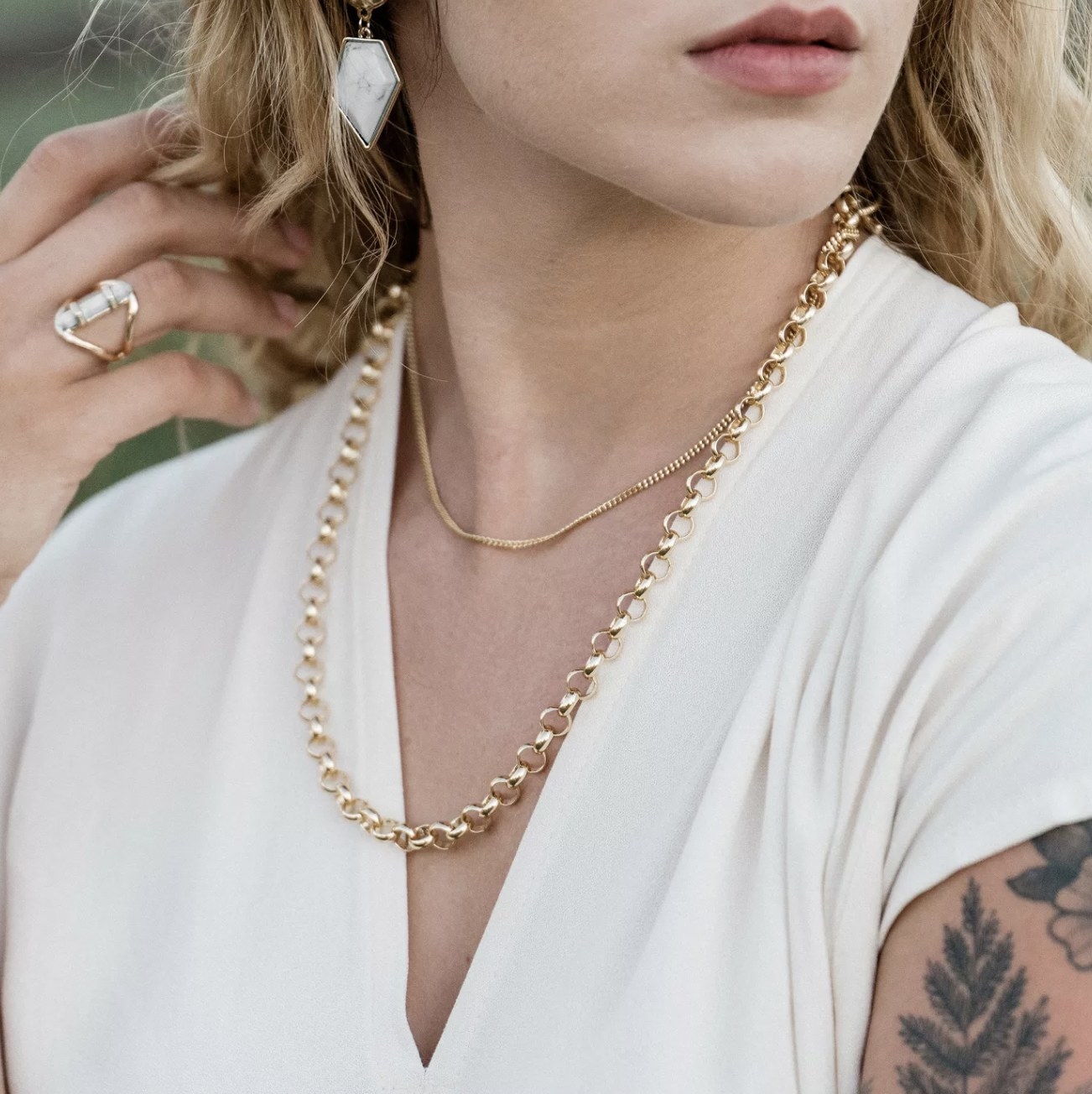 a model wearing a thin gold chain layered with another necklace