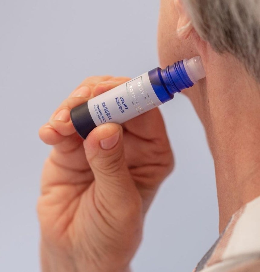 A person applying the rollerball to their neck