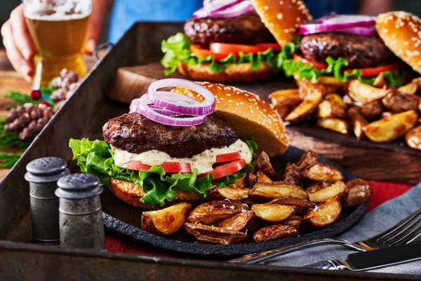 Plates of beef burgers with sides of mini wedges.