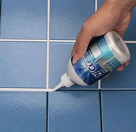 A person applying the grout filler into tile lines 