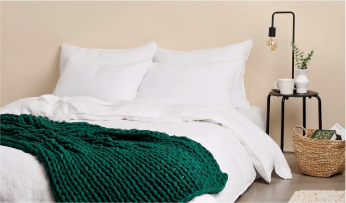 the deep green colored weighted blanket on a bed in a bedroom