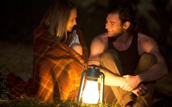 a couple cuddling and smiling in the light of a lantern 