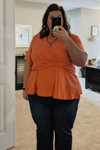 reviewer wearing the peplum top in orange with jeans 