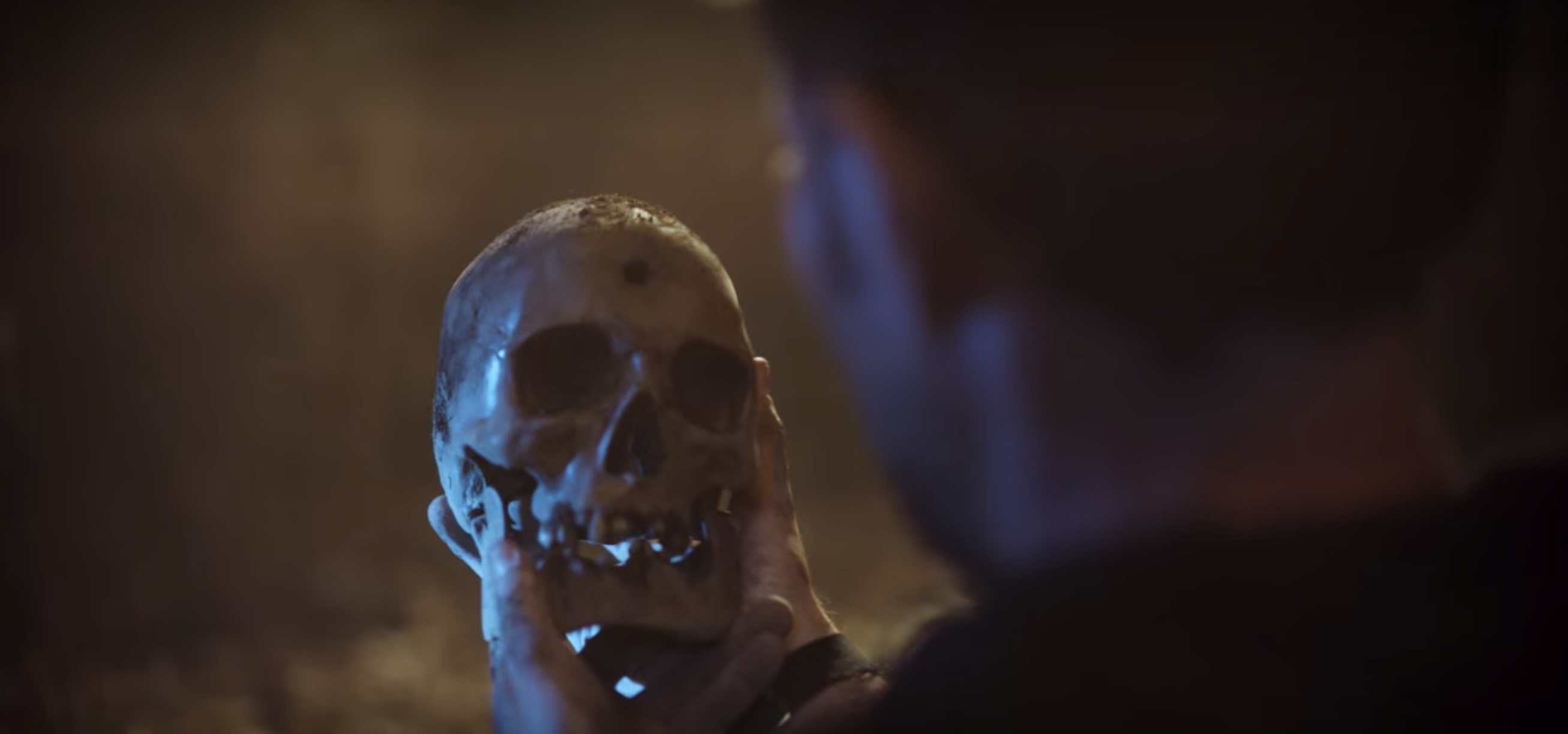 Alex holding a skull with a bullet in the head
