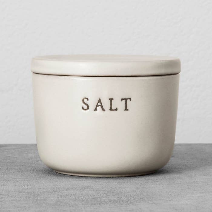 white stone salt cellar with lid and "salt" engraved on the front