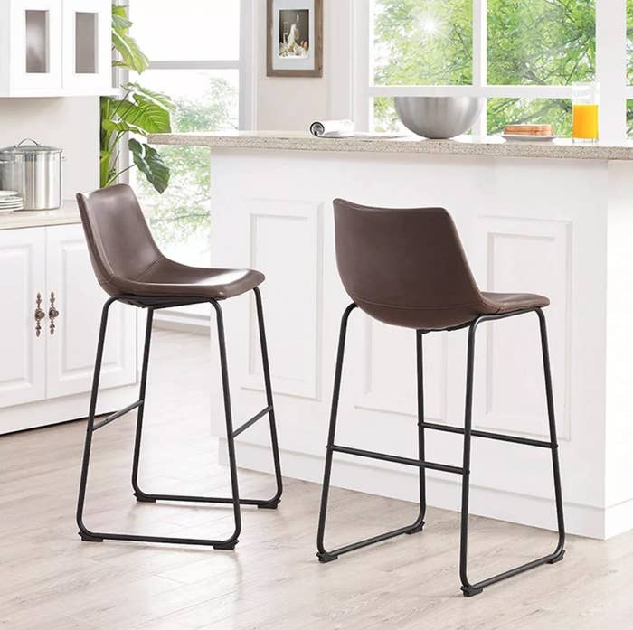 The set of two faux leather bar stools in brown with black metal legs