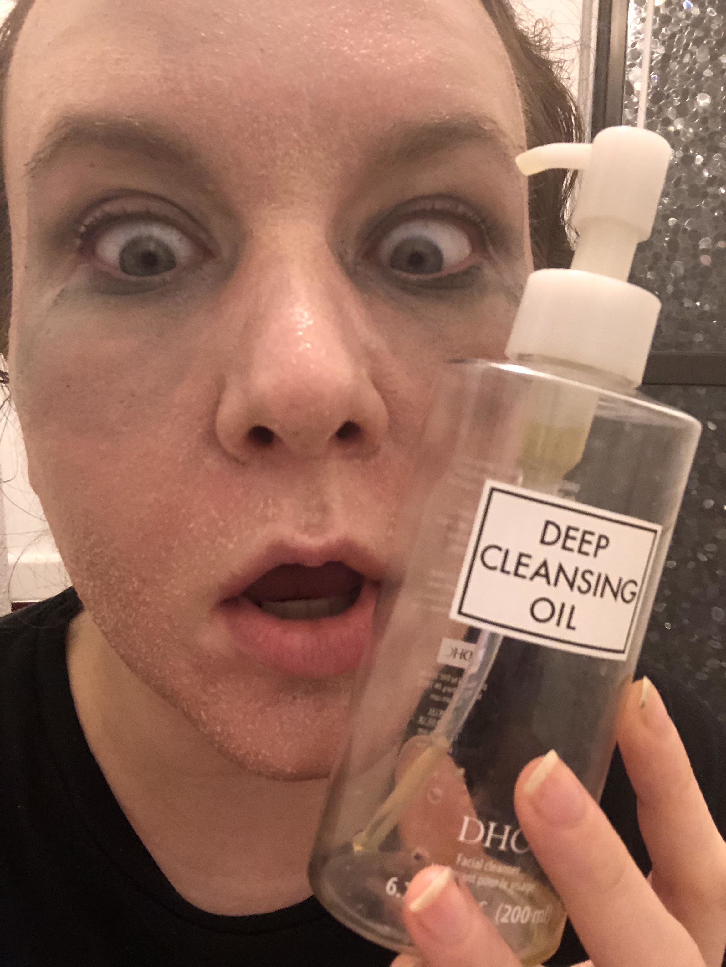 writer with foundation and mascara dissolving on face holding a bottle of the cleanser