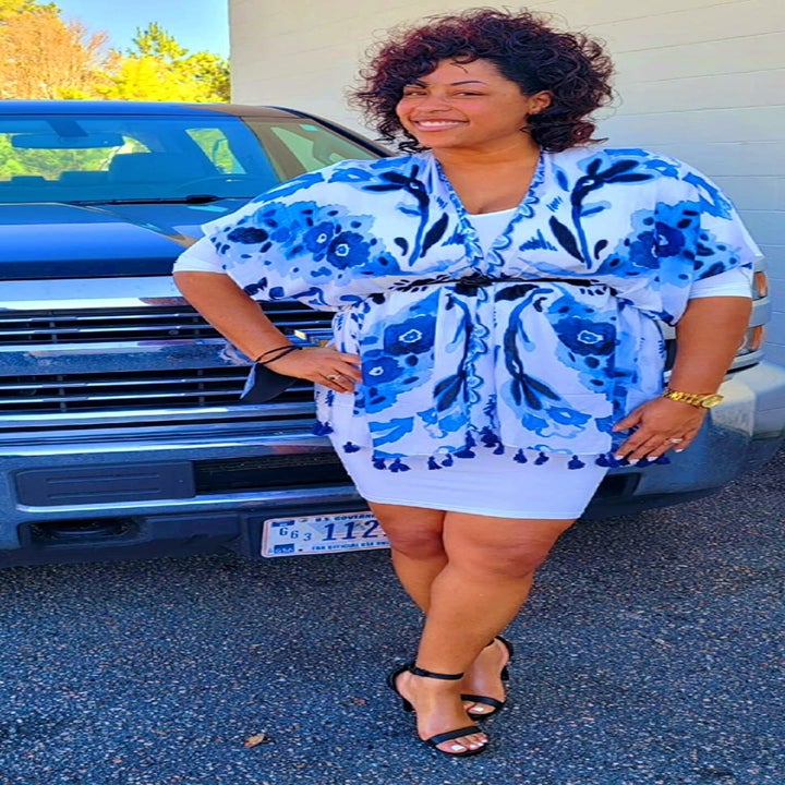 reviewer wearing the blue and white patterned coverup over a dress with a belt