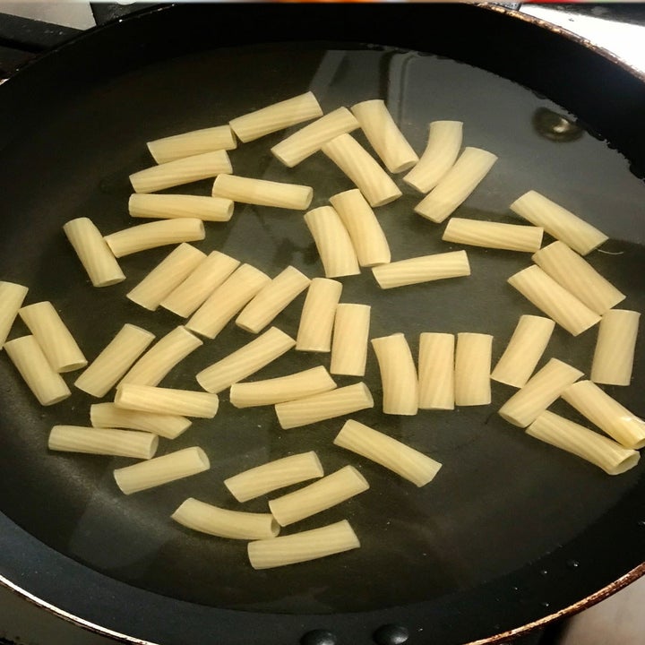 Pasta cooking in a thin layer of water in a skillet.