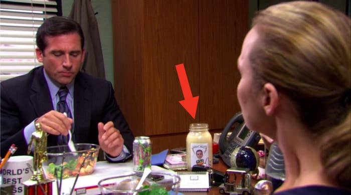 Michael eating and speaking with Jan as the salad dressing bottle sits on his desk