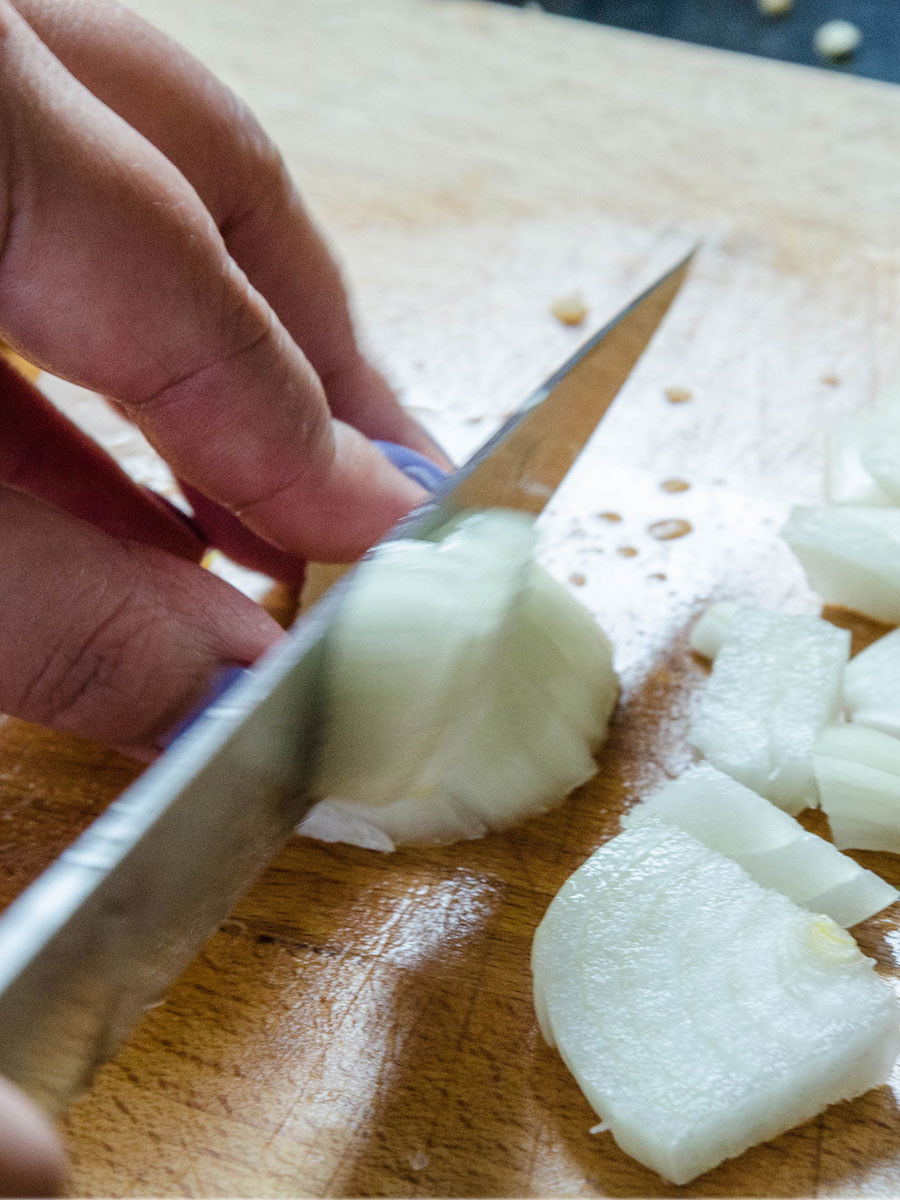 Chopping a white onion on a cutting board.