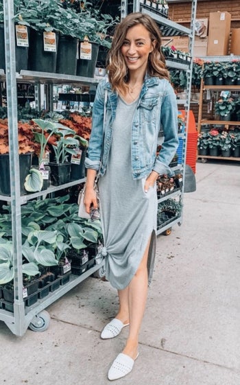 A reviewer wearing a grey maxi dress and denim jacket