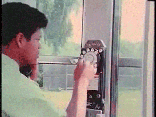 A vintage video of a man using a rotary dial pay phone