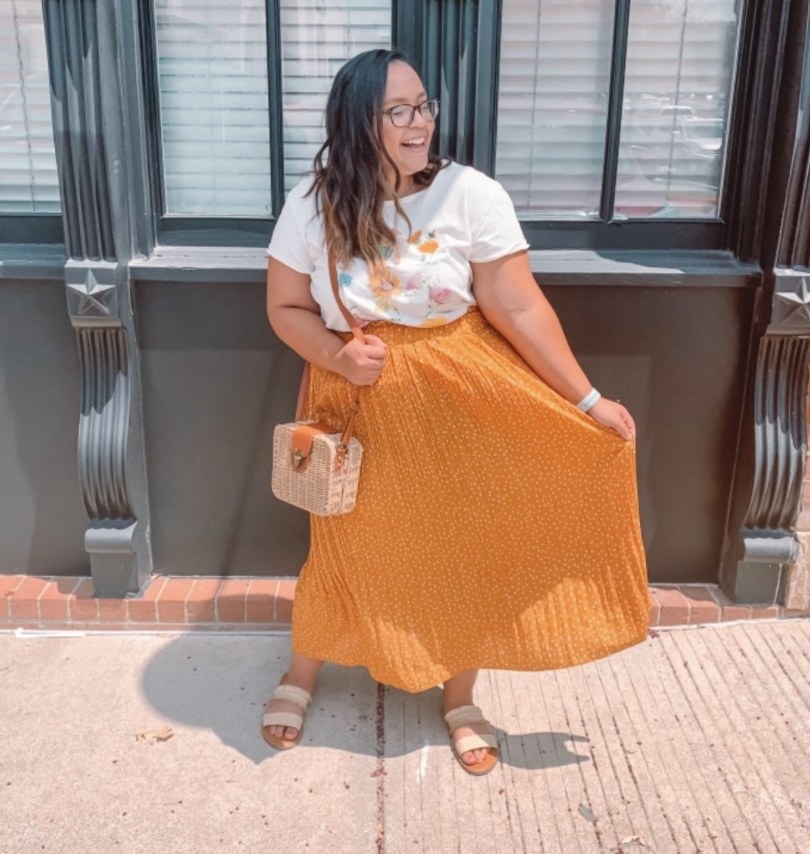 A person wearing an orange maxi skirt and white top