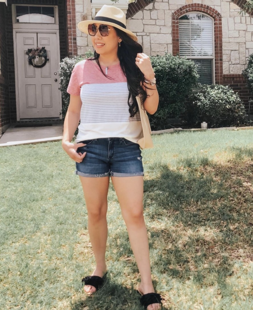 A reviewer wearing a color block T-Shirt with denim shorts