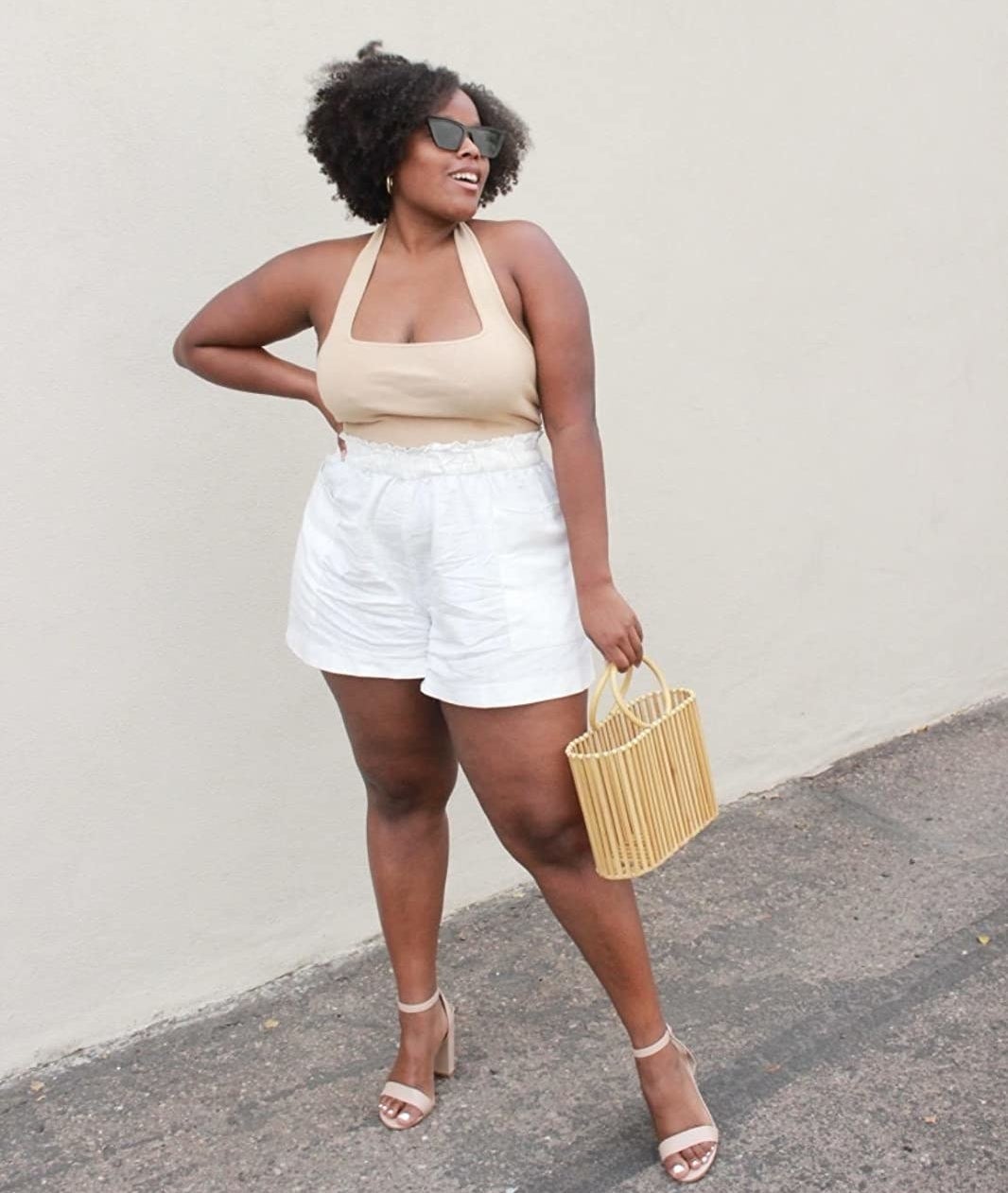 a reviewer wearing the beige top with white shorts