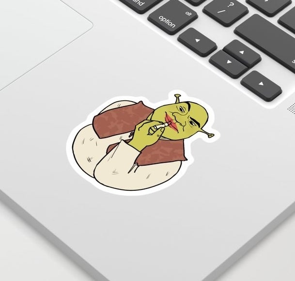 A sticker of Shrek putting lipstick on stuck to a laptop 