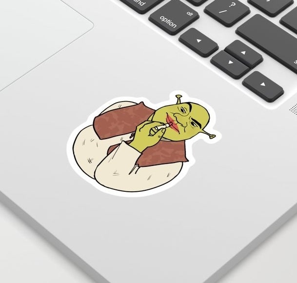A sticker of Shrek putting lipstick on stuck to a laptop