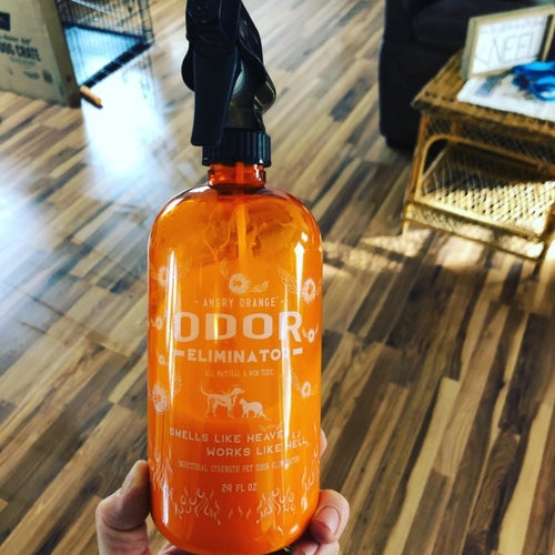 the orange bottle held up in front of a wood floor