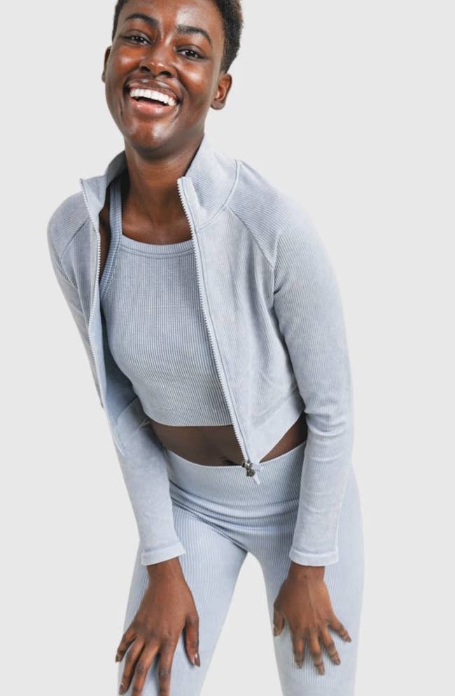 model in light blue cropped front-zip jacket with matching ribbed crop top and leggings