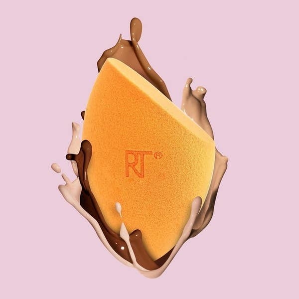 floating orange makeup sponge with foundation on it