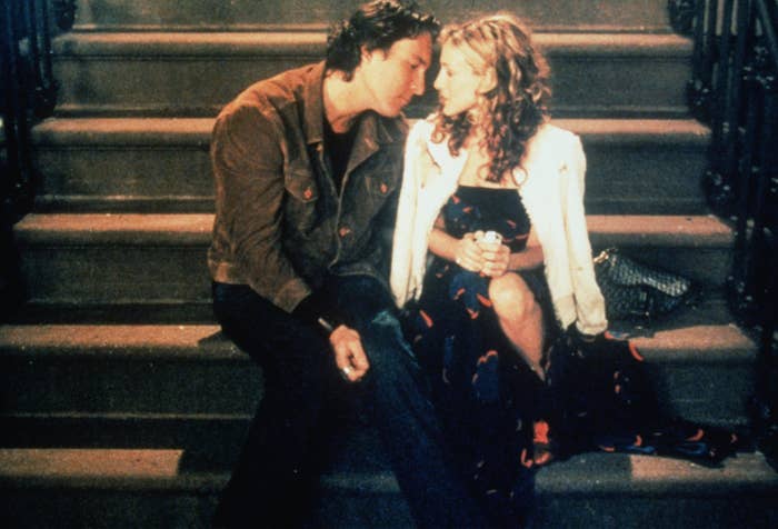 Carrie and Aidan sit on the steps of a building together