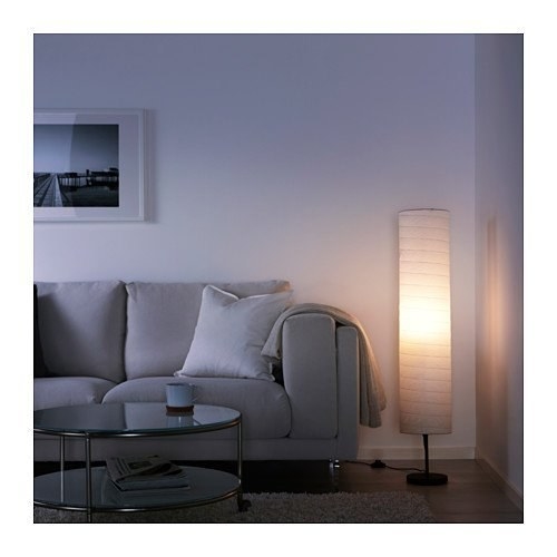 A cylindrical rice paper lamp from Ikea. Its place in the corner of a room, next to a grey sofa.