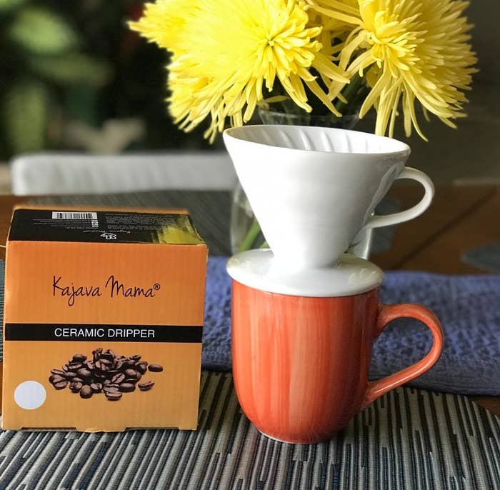 reviewer photo of the white ceramic dripper on top of their orange coffee mug