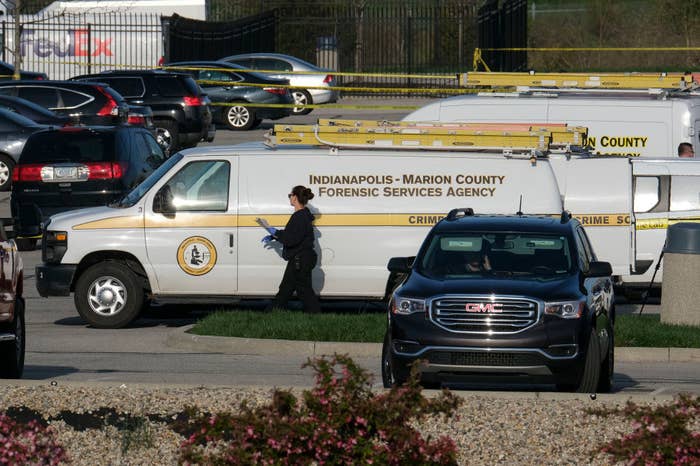 Vans from a forensic services agency are parked near an area that is cordoned off by police tape 