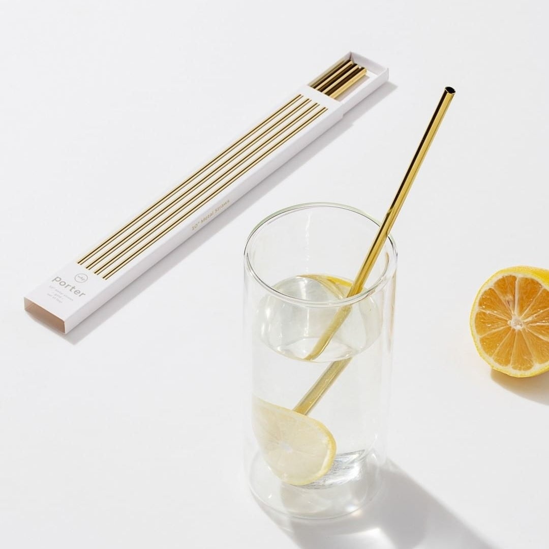 A set of metal straws on a counter next to a glass of lemon water