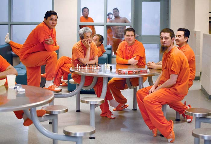 A group of inmates sit around a table while playing games. 