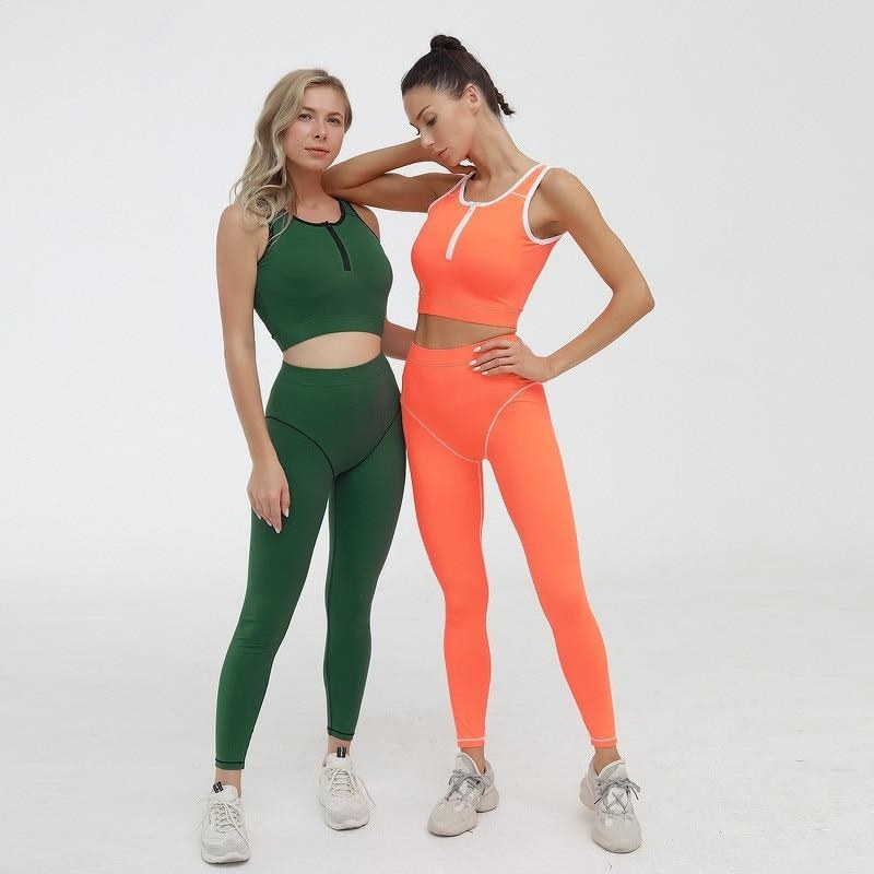 two models, one wearing the green and black color-blocked legging and sports bra outfit and the other wearing orange and white 