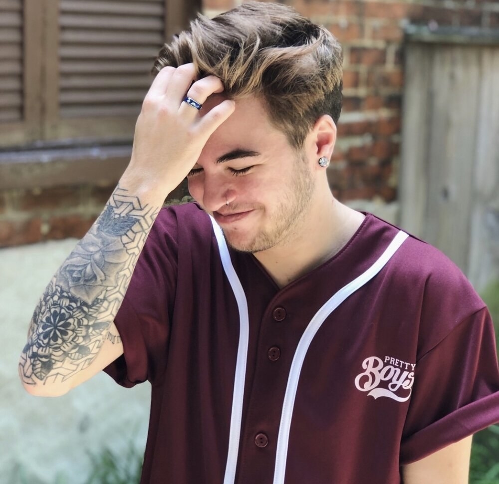 a model wearing the pretty boys baseball jersey in maroon with white lettering and stripes 