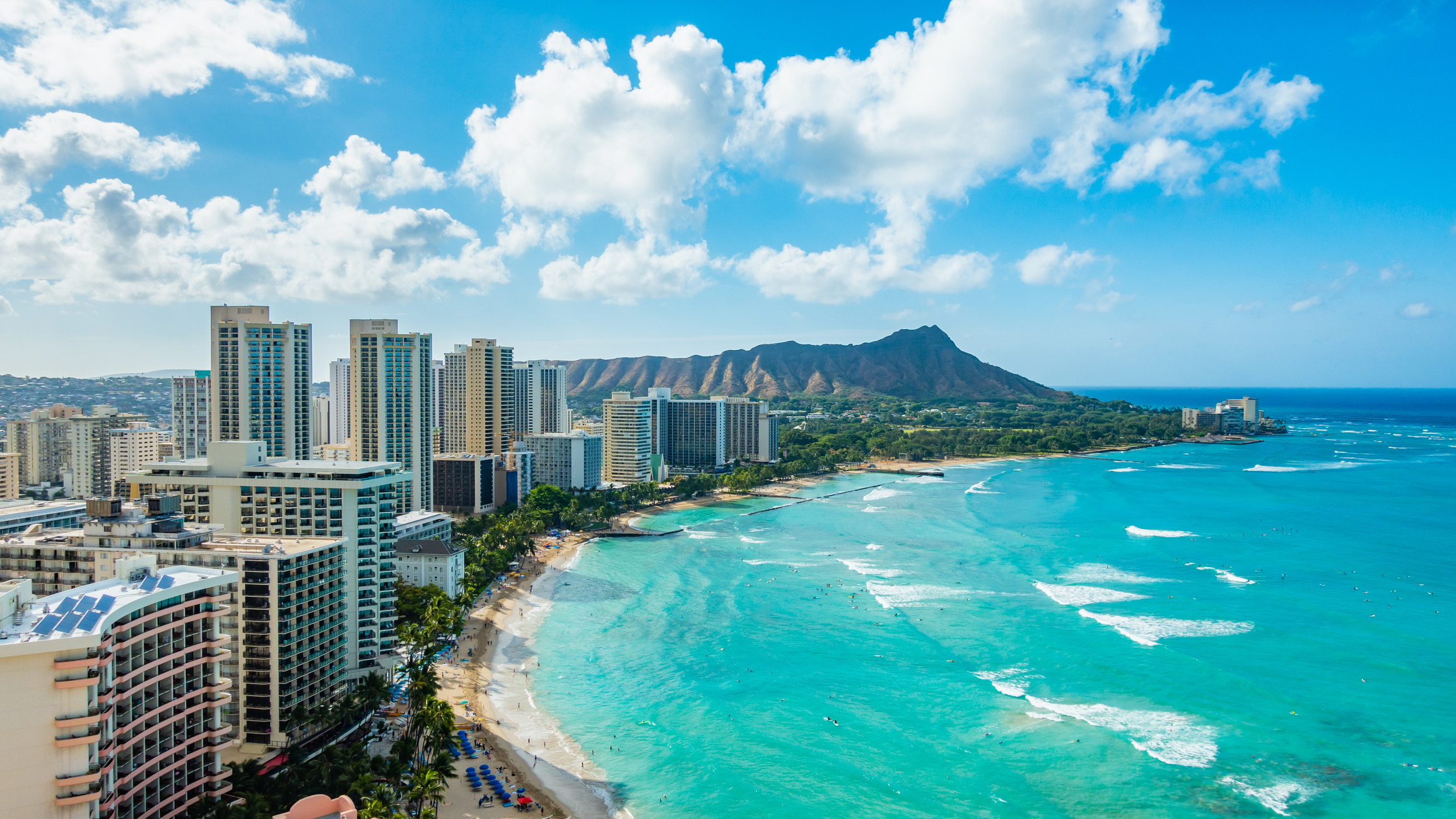 Tall buildings right on the beach in Waikiki with a mountain in the distance