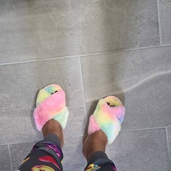 reviewer wearing the criss cross strap slippers in rainbow tie-dye
