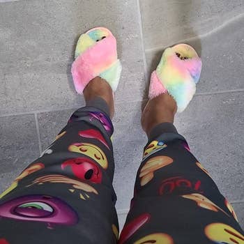 reviewer wearing the criss cross strap slippers in rainbow tie-dye