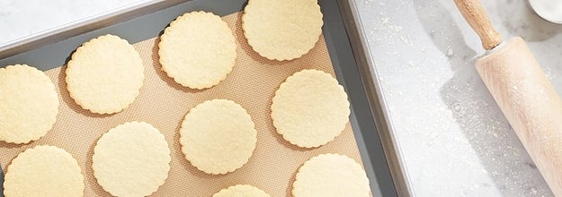 silicone baking mat on a sheet pan with sugar cookies on top