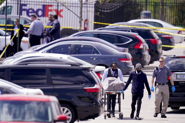 A covered body is carried on a gurney through a parking lot