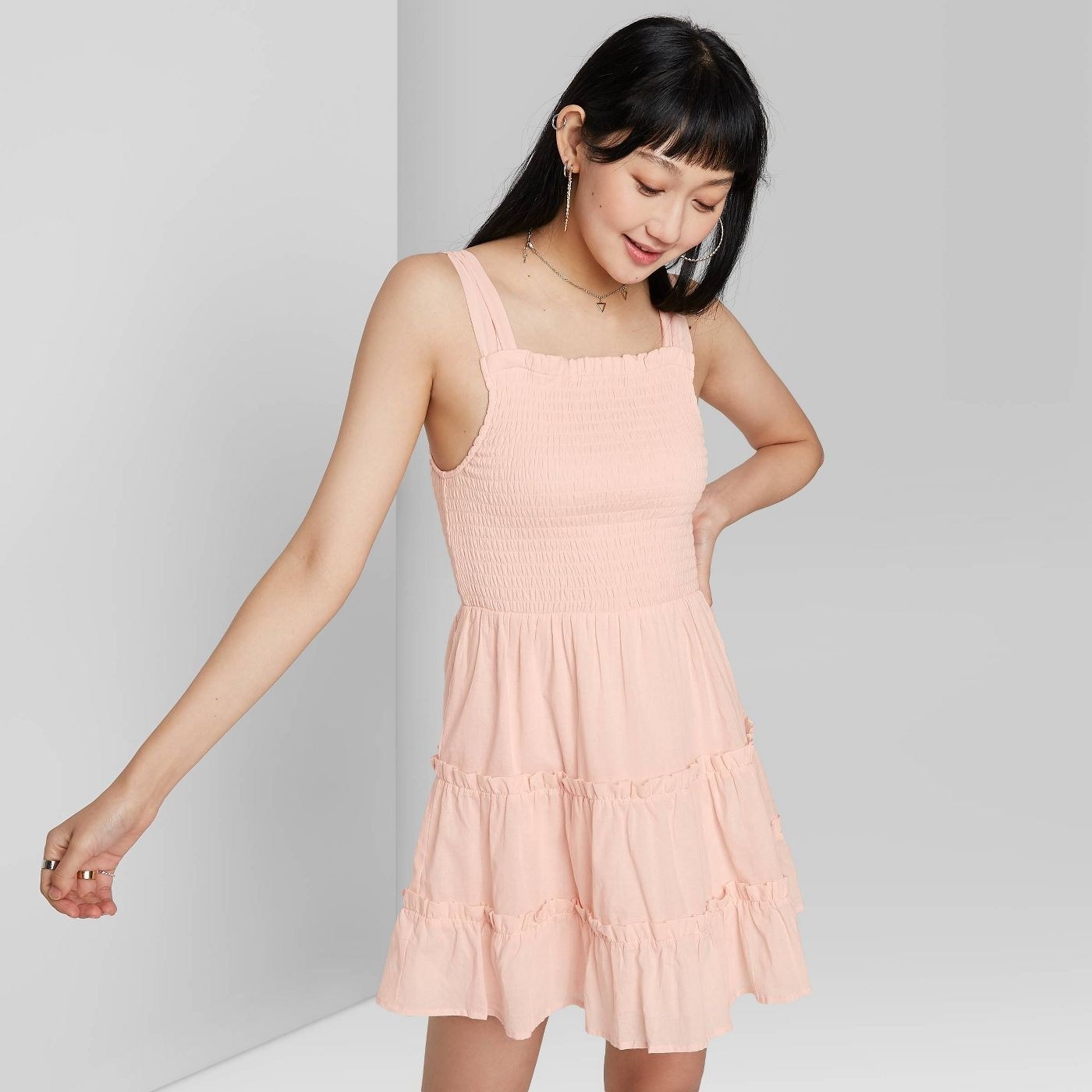 Model wearing sleeveless  tiered dress with smocked bodice