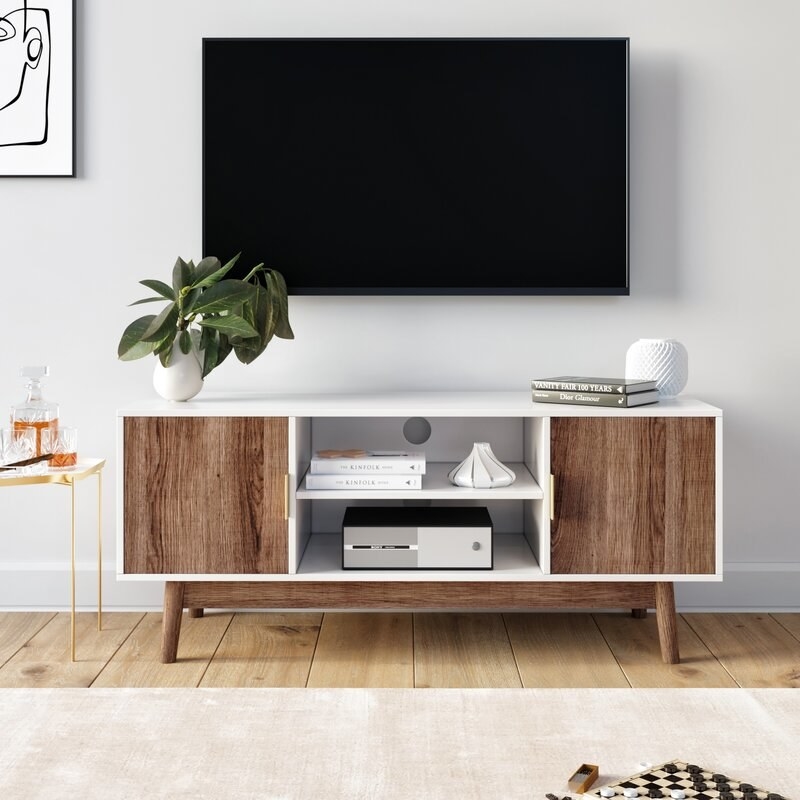 A white and rustic oak tv stand with 2 cabinets and 2 exterior shelves, filled with books, decor, and a stereo system