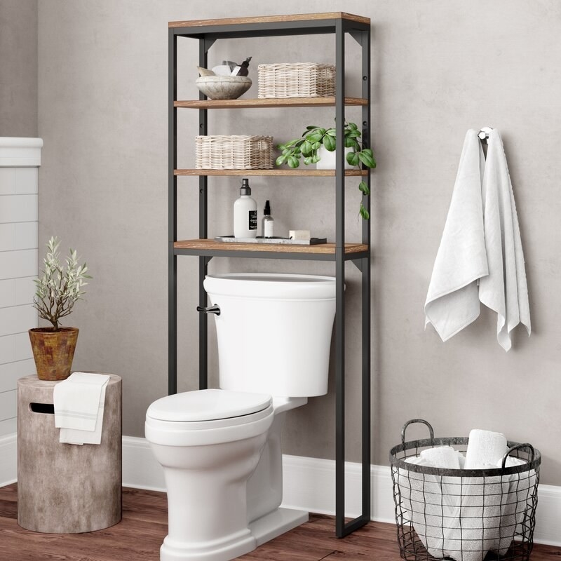 An over-the-toilet shelving unit with 4 shelves that can hold items such as towels, toiletries, soaps, candles, frames, and much more