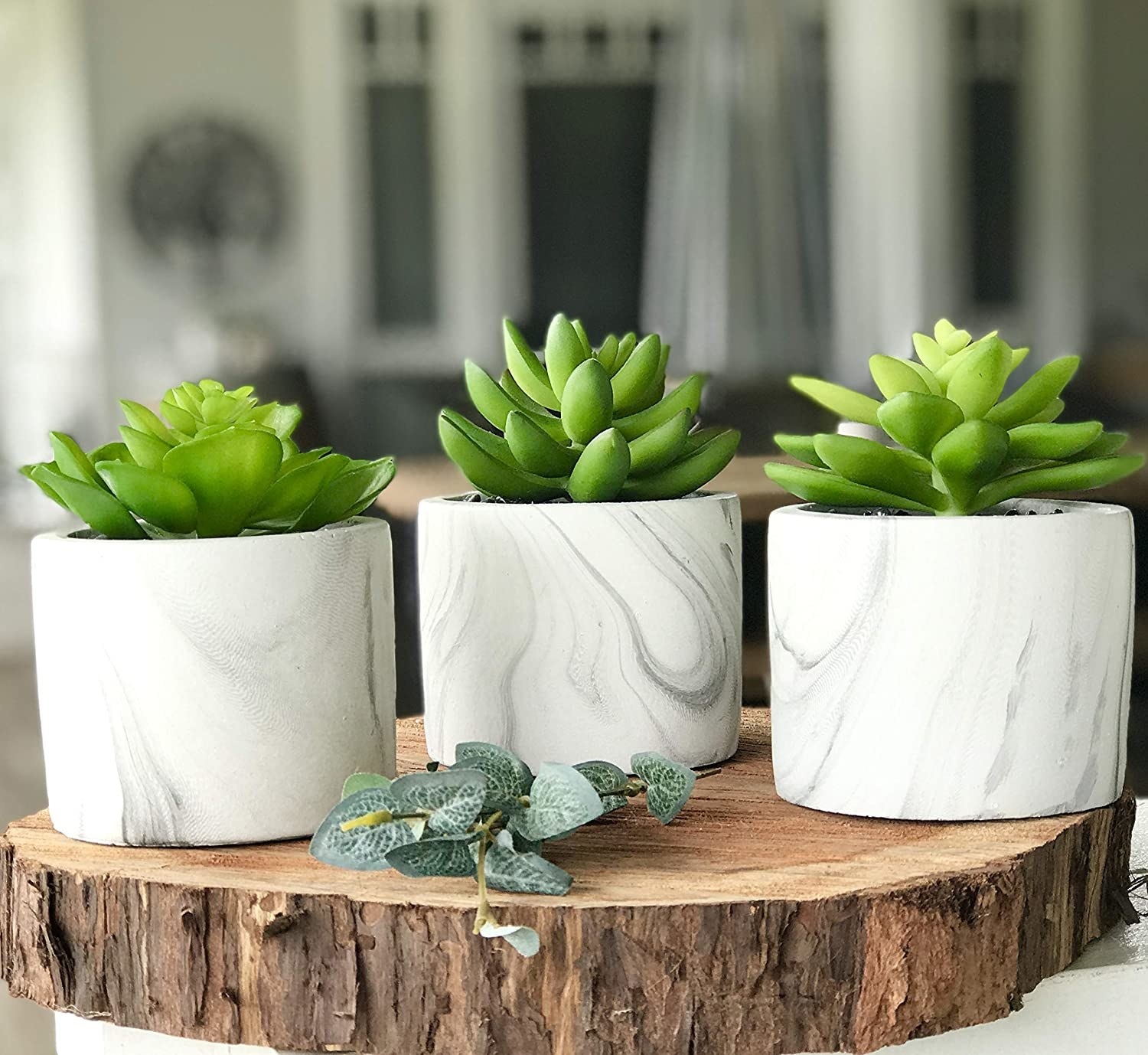 A set of three faux succulents in white marble-style pots