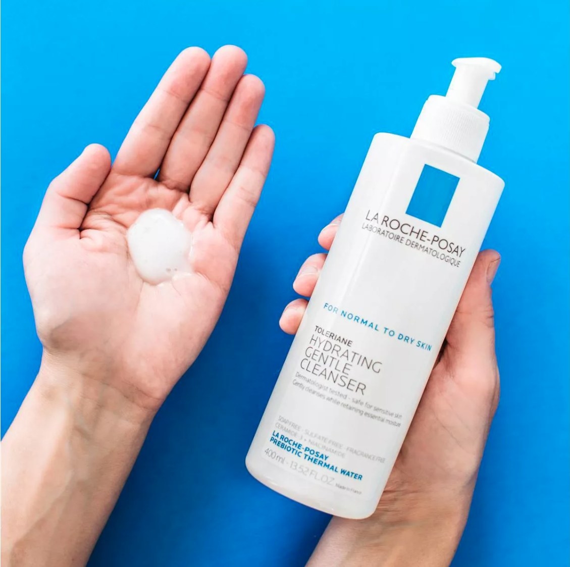 Hand holding cleanser while other hand shows formula in palm