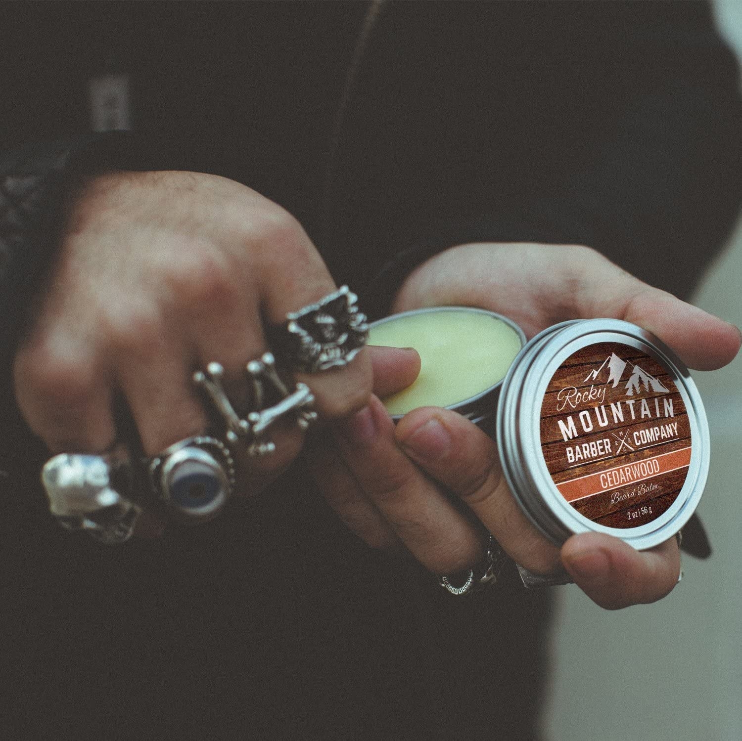 A person holding a metal tin of beard balm