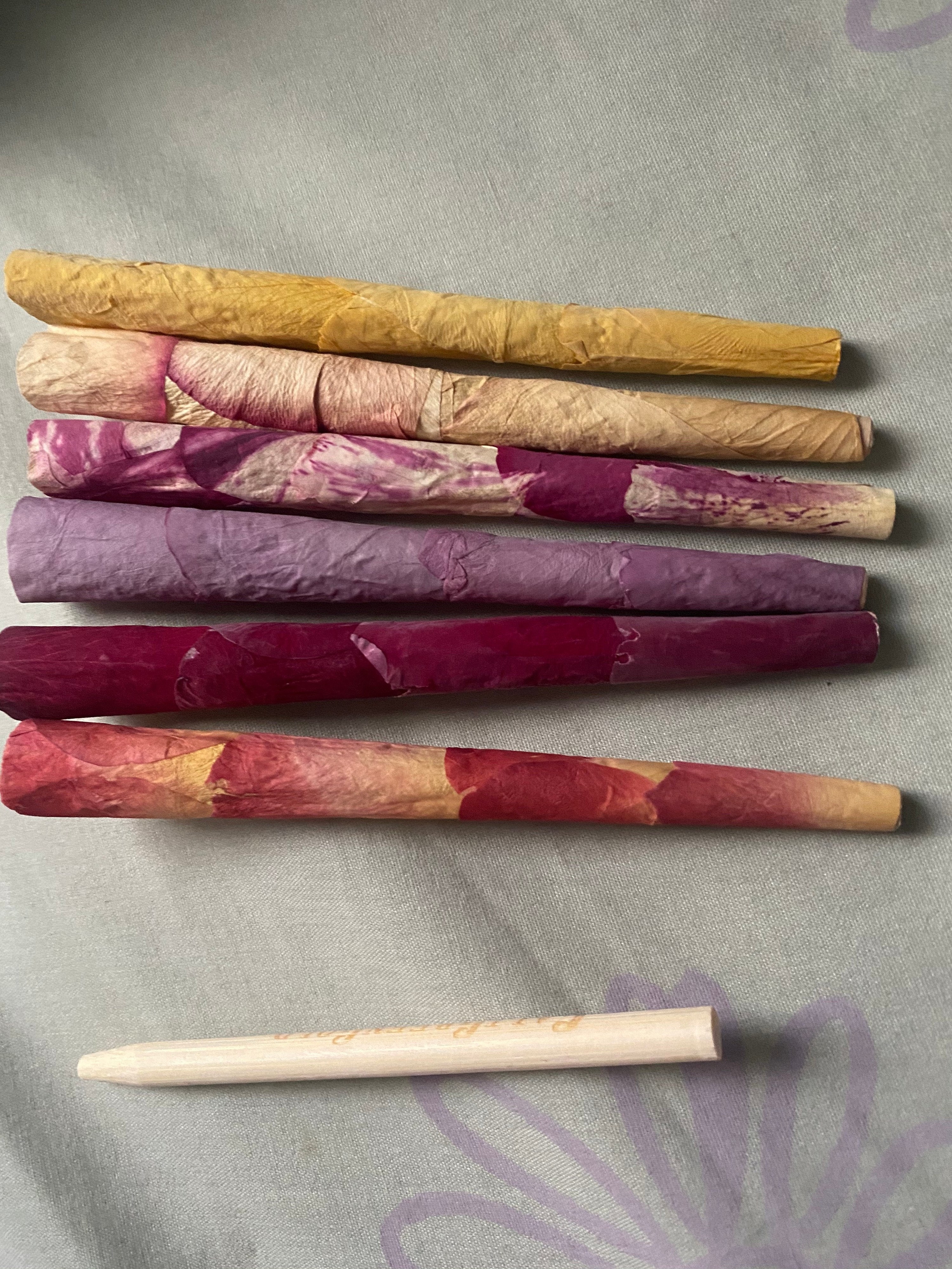 five pre-rolled cones made with rose petals in different colors including purple, pink, and yellow, and orange