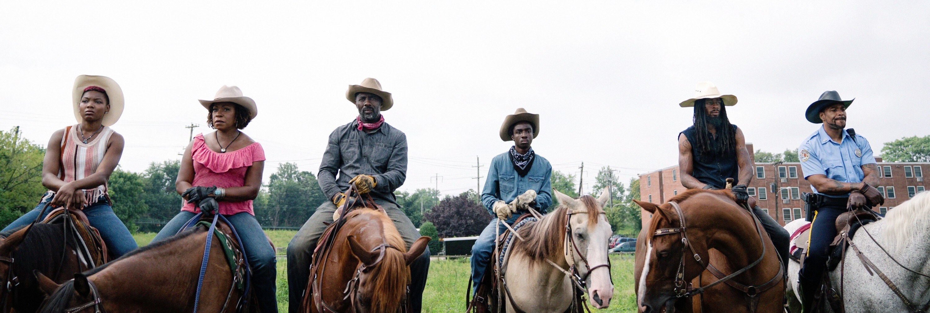 Cowboys and cowgirls sit on their horses side-by-side