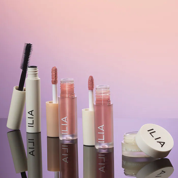 A tube of mascara, lip gloss, eye tint, and a container of lip mask in a row