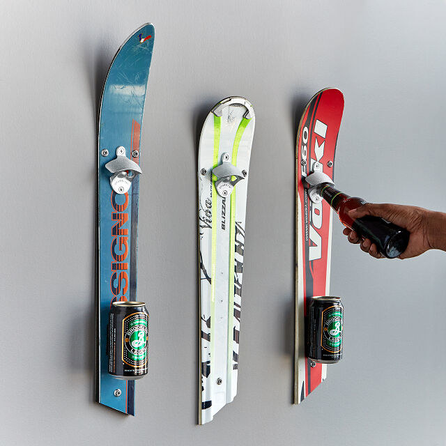 top part of a ski hung on wall with bottle opener attached